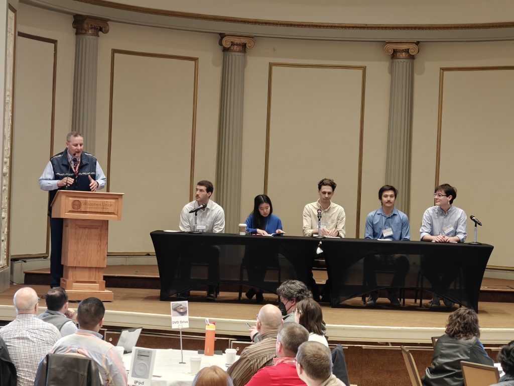 Panel on stage with five panelists and Todd Shechter leading the discussion