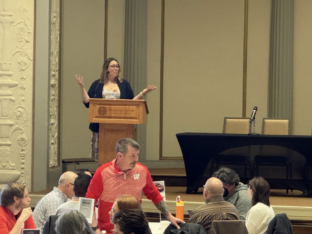 Ella Tschopik delivering the opening speech behind a podium onstage.